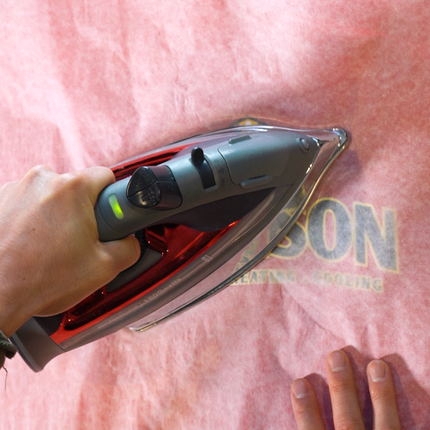 household iron being used to press a DTF transfer